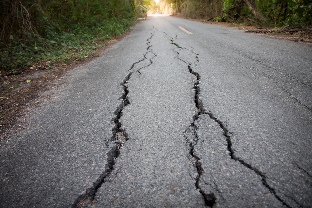 Asphalt road with big cracks that needs reparation.