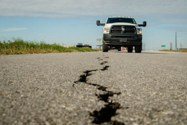 A truck driving on old road with big cracks.