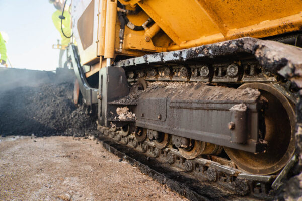 Asphalt paver laying asphalt on the surface of a road.