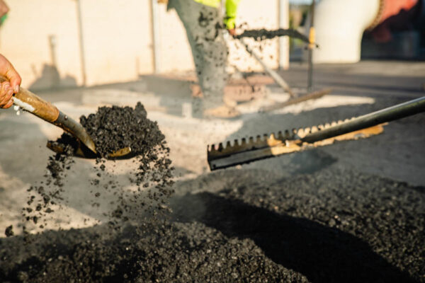 AAA Paving working team smoothens hot asphalt with shovels by hand.