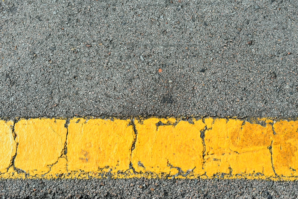 Yellow strip of old road markings on gray asphalt.