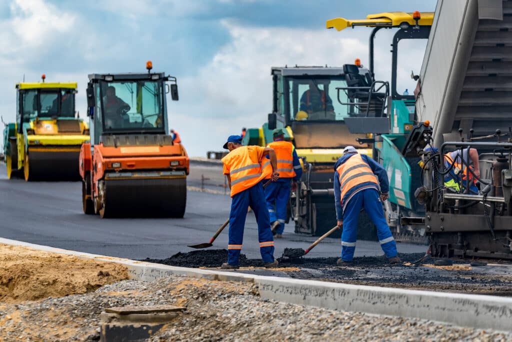 Close view of the workers and the asphalting machines.