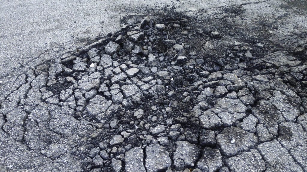 Is Your Asphalt Failing You? Here's a Smarter Way to Fix It. 1 Asphalt paving crew working on large commercial parking lot