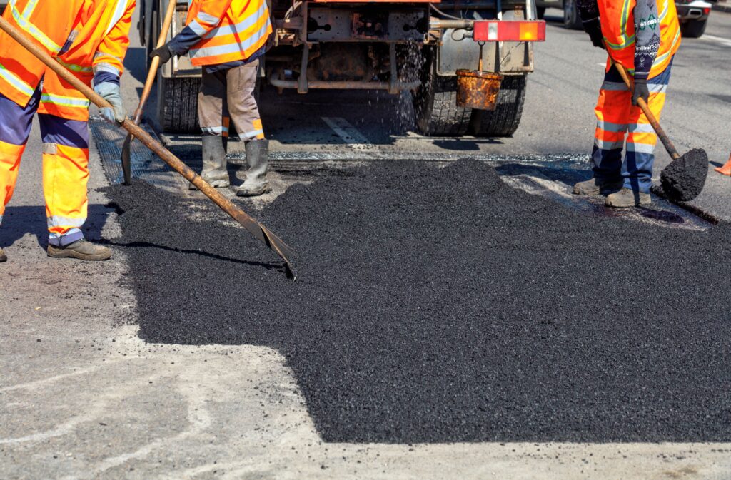 Road workers updating part of the road with fresh hot asphalt and smoothes it for repair